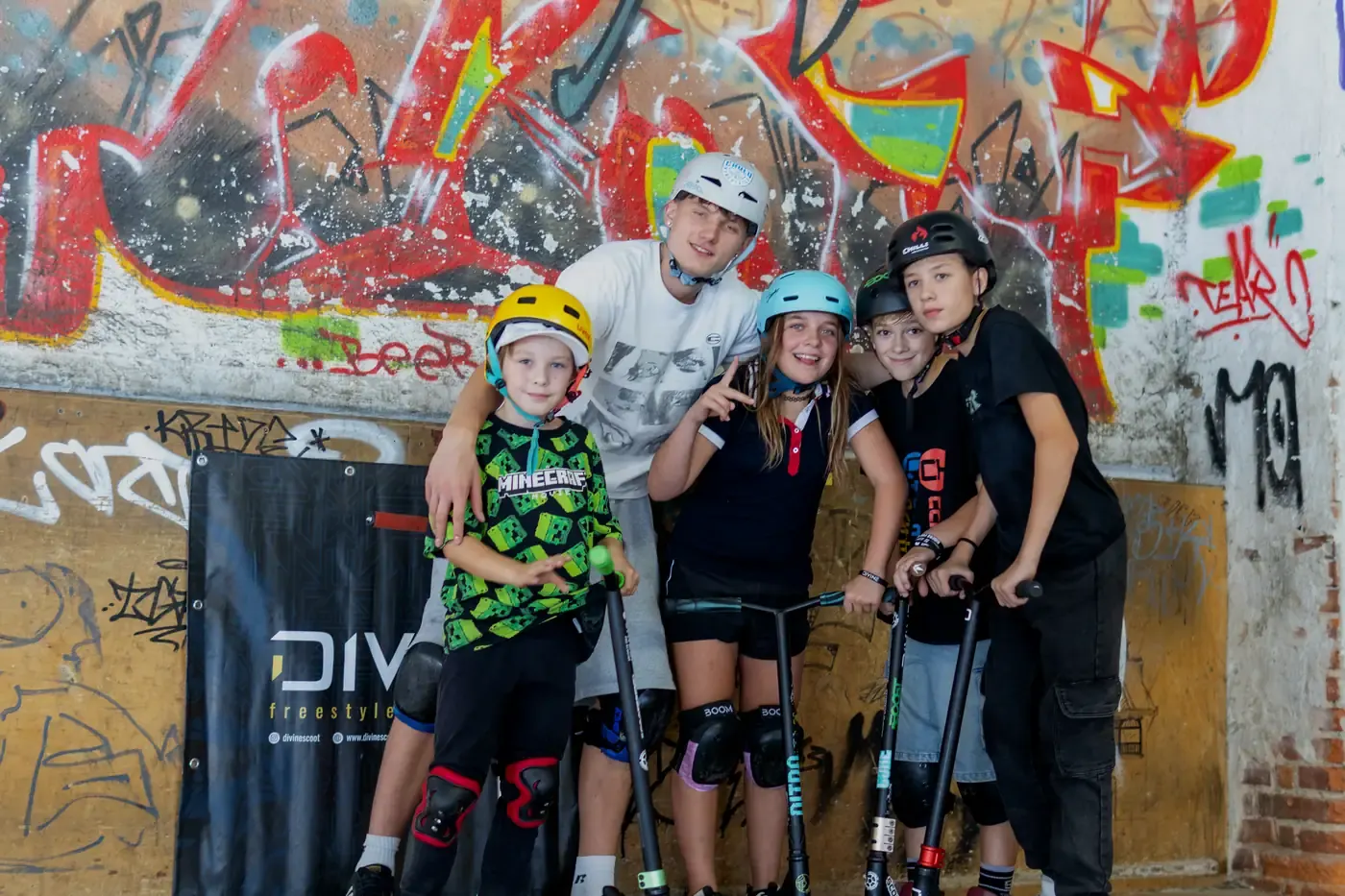Trenér s dětmi u graffiti zdi ve skateparku