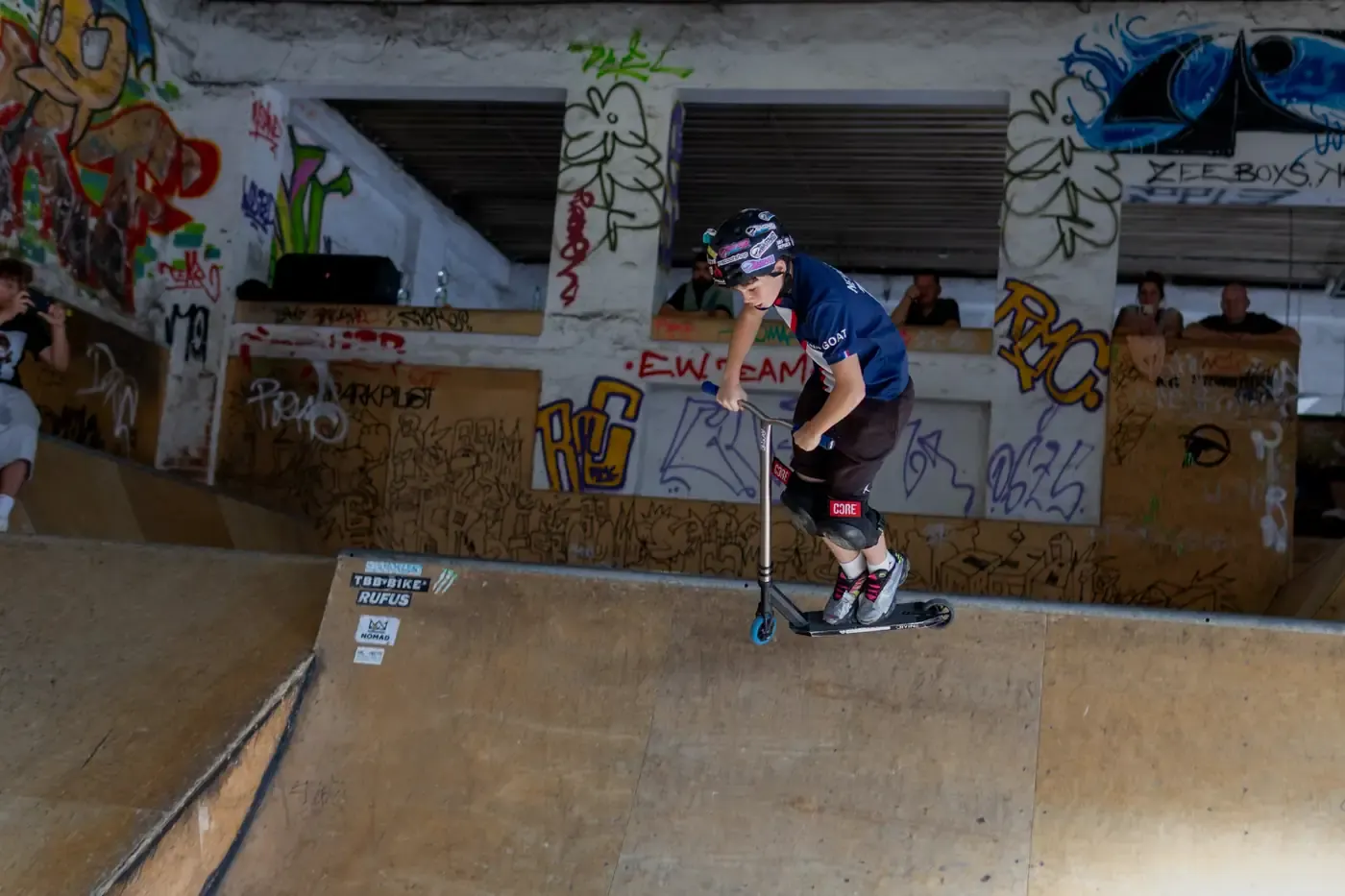 Jezdec projíždí trik na rampě v hale skateparku